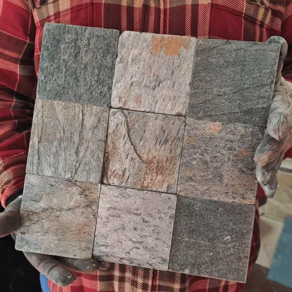 Muestra sostenida de mosaico formado por nueve piezas cuadradas de piedra