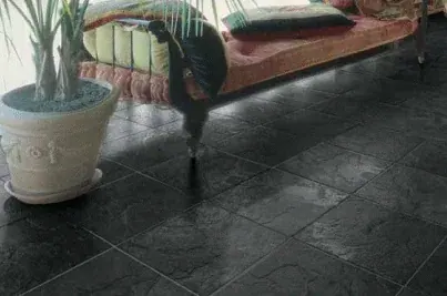 Piso de piedra pizarra oscura con juntas visibles junto a un sofá y una maceta