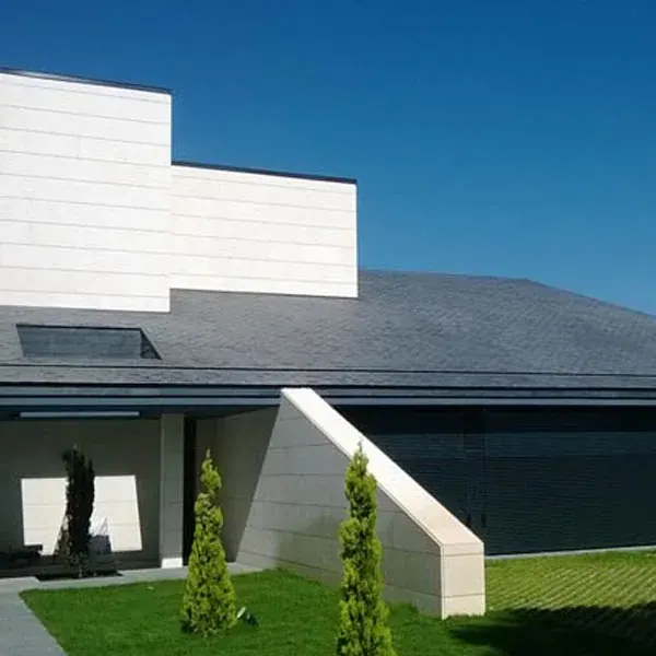 Vivienda con techo inclinado de piezas oscuras junto a volúmenes claros