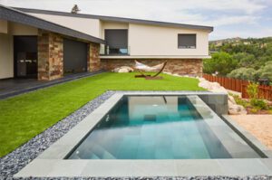Vista exterior de jardines y piscina revestida con pizarra gris verde